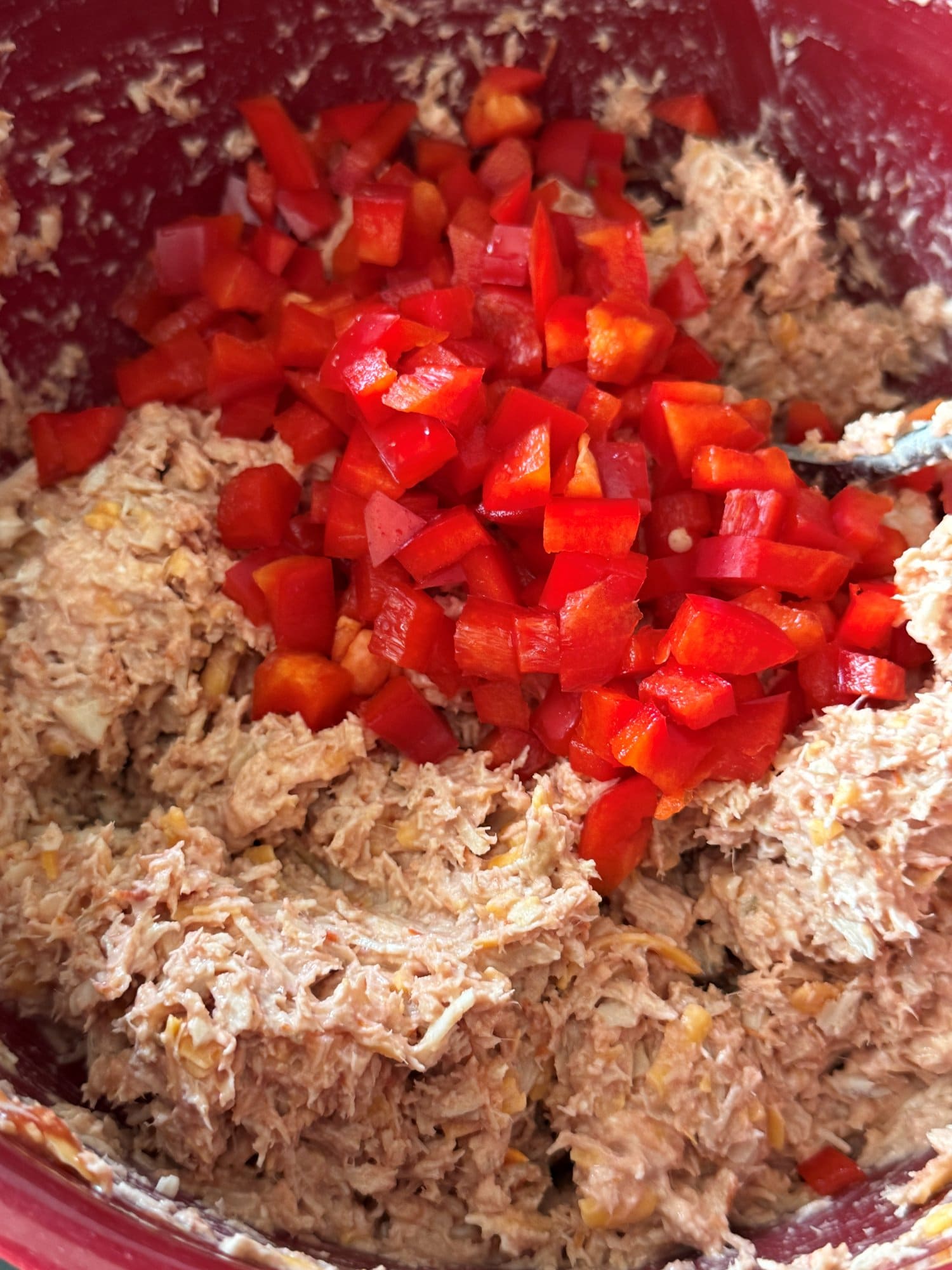 Diced red pepper sitting on top of the mixed chicken filling, ready to be stirred in